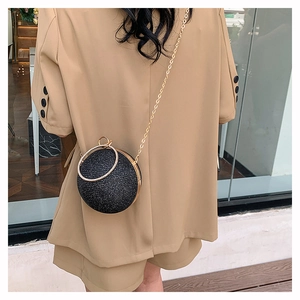 Détail du sac de soirée rond à paillettes noires avec poignée dorée et chaîne