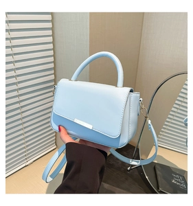 Detail einer hellblauen Lederhandtasche mit Silberbesatz und rundem Tragegriff