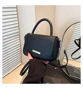 Détail d'un sac à main noir avec barre métallique dorée claire et poignée ronde