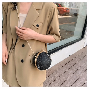 Sac de soirée sphérique à paillettes noires et chaîne dorée avec un blazer beige