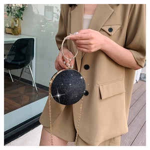 Détail d'un sac de soirée noir pailleté avec poignée strass et chaîne dorée