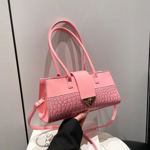 Sac à main rose à motif crocodile avec fermoir triangulaire doré porté par mannequin