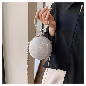 Détail d'un sac de soirée sphérique argenté scintillant avec poignée circulaire dorée