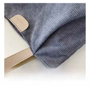 Detail of blue-grey corduroy tote bag featuring leather straps and fashion label
