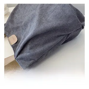 Detail shot of gray corduroy fabric texture and leather 'FASHION' tag on tote bag