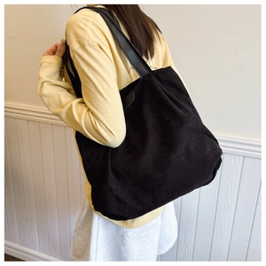 Close-up of black corduroy tote bag texture with leather straps and Fashion label