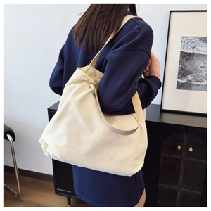 Close-up of off-white corduroy tote bag showing vertical rib texture and fabric strap