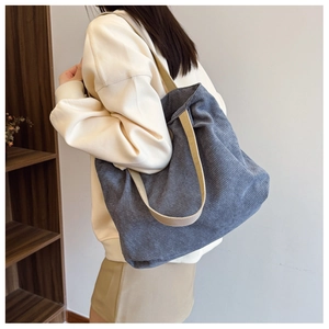 Detailed close-up of dark blue corduroy tote bag with cotton strap on woman's shoulder