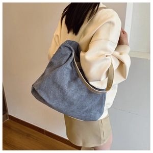 Close-up of blue corduroy tote bag texture and khaki strap shown on model's shoulder