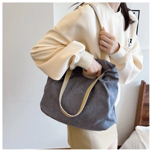 Detail of grey corduroy tote bag with beige straps shown in a minimalist indoor setting
