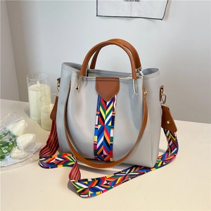 Light gray leather handbag with geometric woven strap and top handle in a lifestyle setting