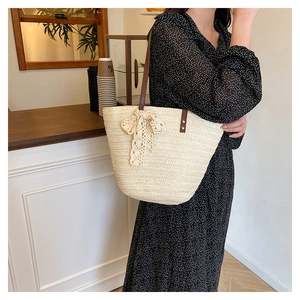 Detail of straw tote bag with cream lace bow and premium brown leather handles