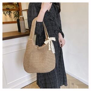 Sac fourre-tout en paille avec nœud en dentelle blanche porté par un mannequin en été