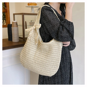 Detail shot of woven tote bag featuring a large bow and beige artisanal textures
