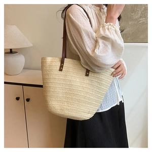 Détail du sac cabas en paille avec bandoulière en cuir et rivets métalliques vintage