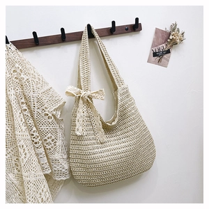 Détail d'un sac cabas en paille tressée beige avec un nœud en dentelle élégant