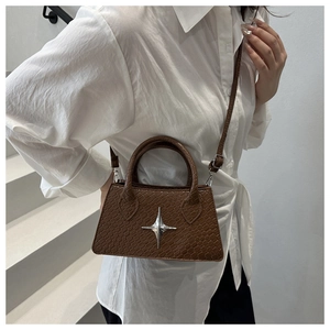 Close-up of brown crocodile pattern handbag with silver star buckle worn by a model