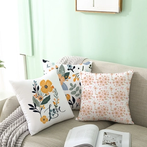 Three decorative floral peach skin pillows on a sofa with green leaf and love patterns