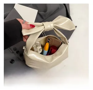 Detail of cream bow handbag interior showing storage capacity for essentials and zipper closure