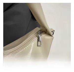 Detail of silver zipper and square metal puller on creamy white faux leather tote bag