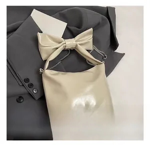 Detail of cream glossy leather tote featuring a large decorative bow and silver chain strap