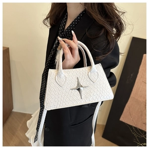 Detail of white woven crossbody bag with silver star ornament held by model