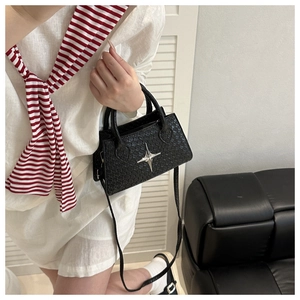Close-up of woven black crossbody bag featuring a metallic silver star emblem and handle