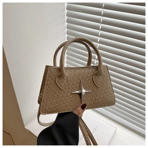 Close-up of woven leather texture and silver star detail on a beige crossbody handbag