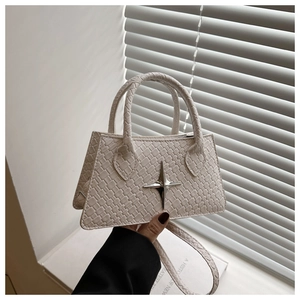 Close-up of a white woven texture trapezoid handbag with a silver star logo and handles