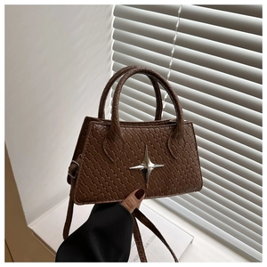 Detail of brown woven leather handbag featuring a silver star buckle and fine texture