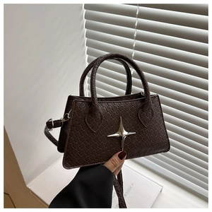 Detailed view of woven texture and silver star metal buckle on dark brown crossbody bag