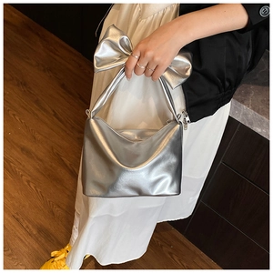 Detail of the oversized silver bow decoration on a metallic textured shoulder bag