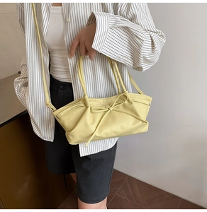 Detailed view of light yellow pleated tote bag with bow detail held by a model