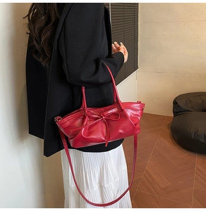 Vue détaillée d'un sac à main rouge avec nœud, porté par un mannequin en veste noire