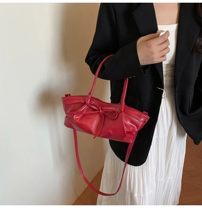 Red bow handbag with leather finish styled on a model wearing a black blazer and white skirt