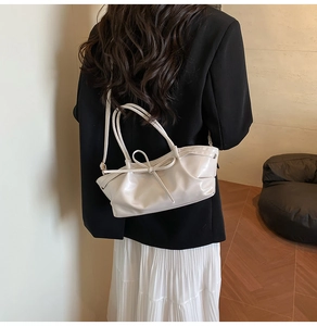 Detail of a beige bow-knot handbag made of soft synthetic leather with a slim shoulder strap