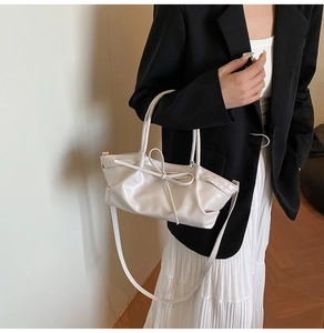 Détail du sac à main crème à nœud papillon avec texture plissée et bandoulière amovible