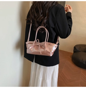 Pink metallic handbag featuring pleated details and bow accents worn with a black blazer