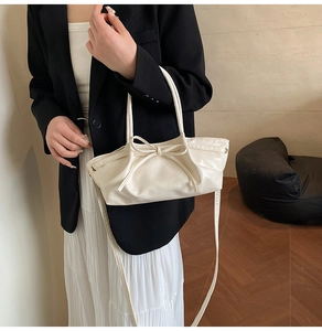 Détail du sac à main crème avec nœud montrant la texture plissée et les poignées