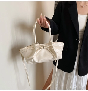 Détail d'un sac à main en cuir PU blanc crème avec un grand nœud décoratif et fines anses