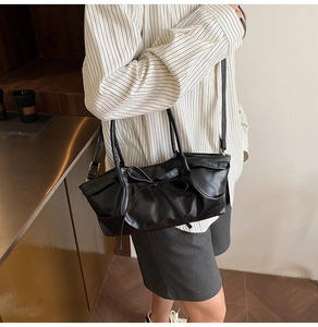 Détail du sac à nœud noir avec bords à volants et texture en cuir synthétique lisse