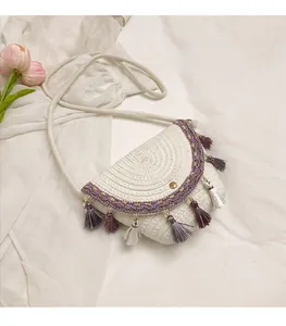 Détail d'un sac en paille bohème avec franges à glands violets et motifs géométriques
