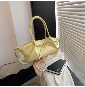 Détail du sac à main jaune clair avec design plissé et nœud décoratif en cuir synthétique