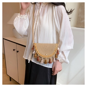 Détail d'un sac à bandoulière en paille tissée avec pompons et broderies