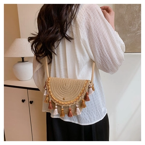 Detail of woven straw saddle bag with ethnic embroidery and colorful cotton tassels
