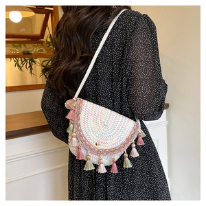 Détail du sac de selle en paille bohème avec glands colorés et broderie géométrique