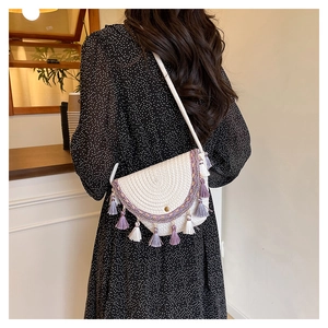 Détail du sac de selle en paille bohème avec broderie florale violette et glands décoratifs