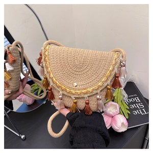 Detail of hand-held straw envelope bag with gold lace and colorful tassel fringe charms