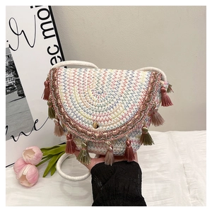 Detail of woven straw envelope bag featuring colorful wavy embroidery and pink tassels