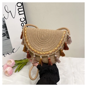 Detail of straw woven envelope bag with colorful tassels and golden embroidery accents